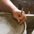 Stephen Earp doing sgraffito on a plate at the treadle wheel; Redware pottery; 2009: Shelburne Falls, Massachusetts; Clay